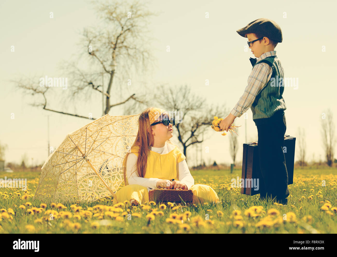 Courtiser une fille petit garçon du parc dans une prairie de fleurs.vintage-look Banque D'Images