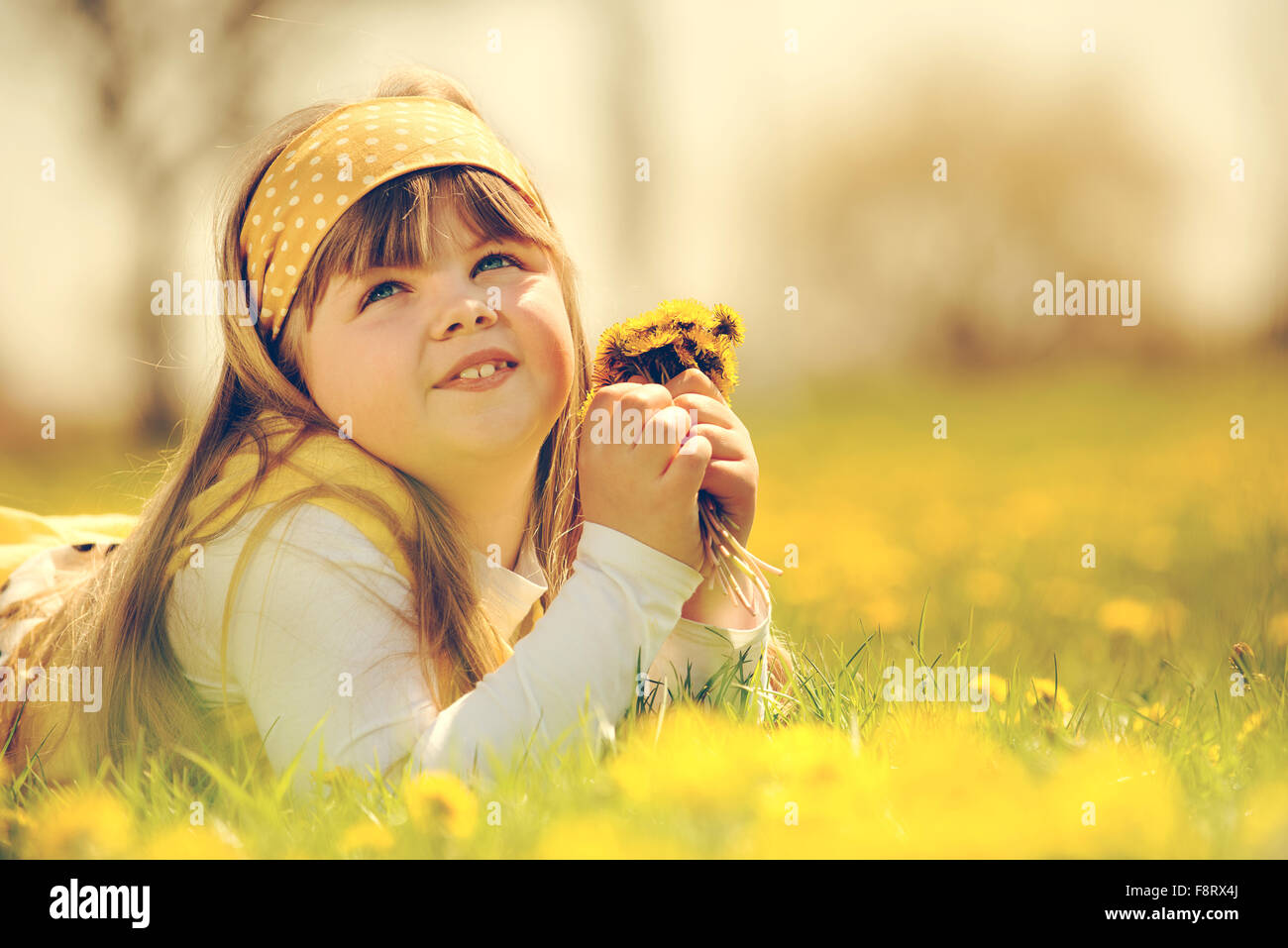 Petite fille profiter de la journée de printemps ensoleillée dans les champs de fleurs. vintage-look Banque D'Images