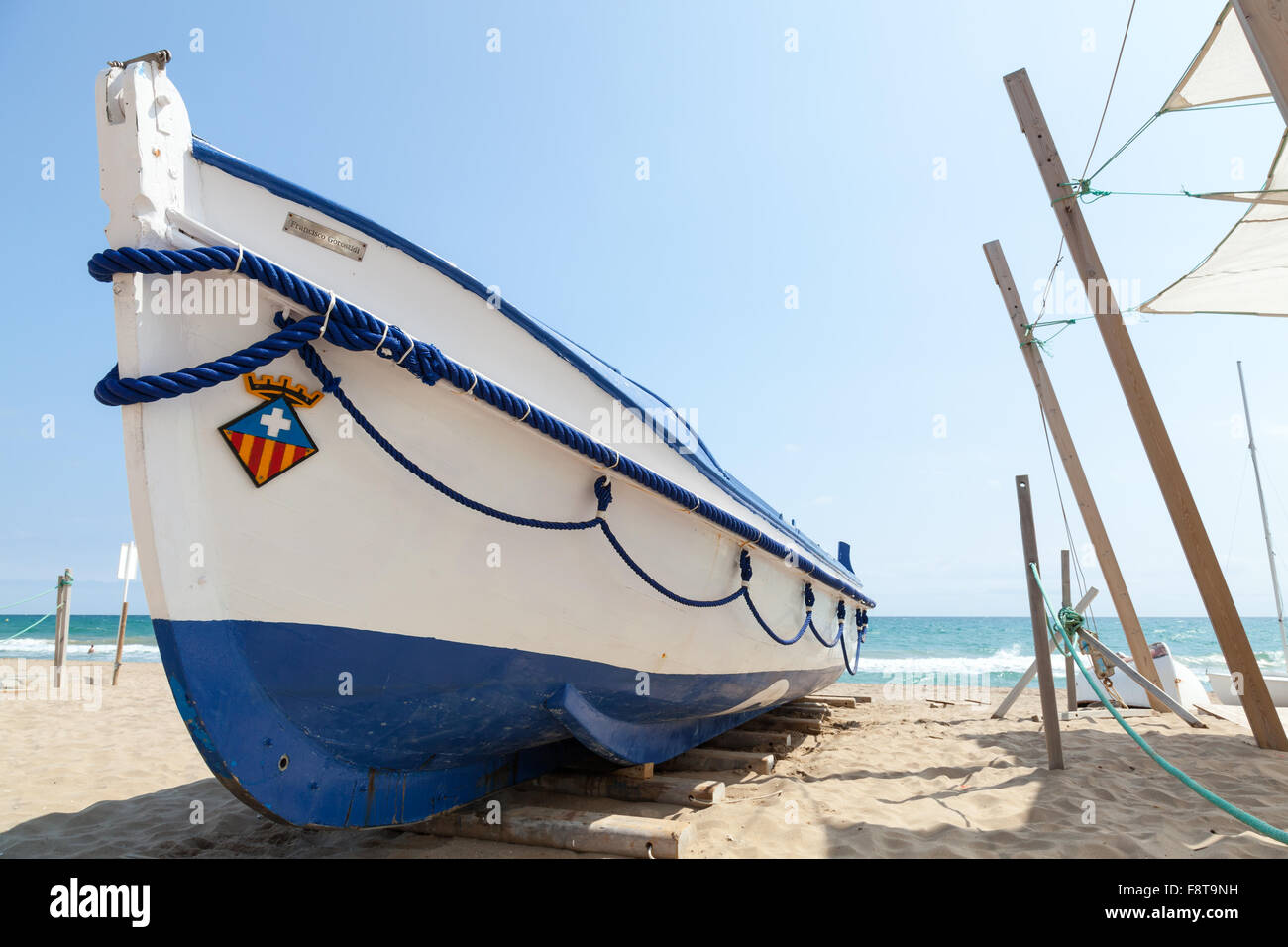 Calafell, Espagne - 20 août 2014 : bateau de pêche en bois blanc s'étend sur une plage de sable, mer Méditerranée, côte de l'Espagne Banque D'Images