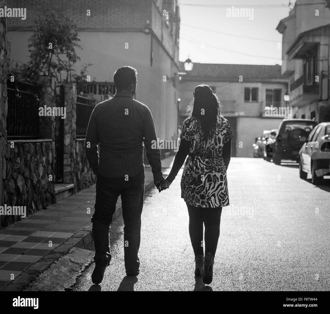 Deux jeunes amants tenir la main dans la rue avec le dos à la caméra. Traitement noir et blanc s'ajoute à l'atmosphère. Banque D'Images