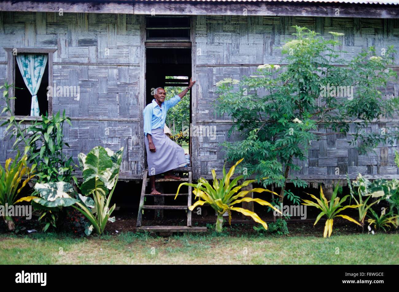 Vue de la vie quotidienne en Ninroa Village un dimanche matin. Adultes masculins portant des peuplements de sulu dans porte de sa bure. Banque D'Images