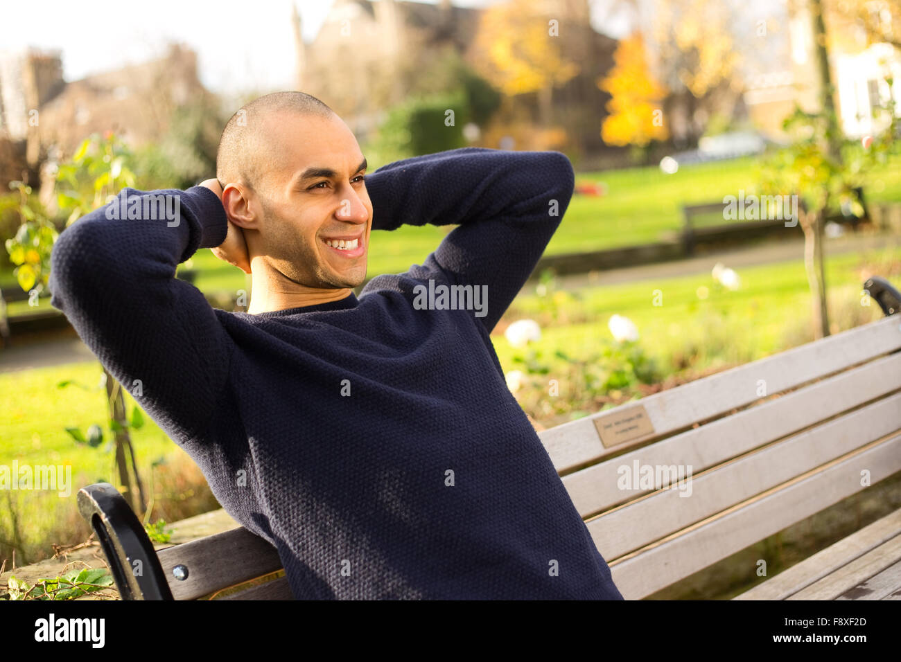 Jeune homme assis sur un banc de parc détendue Banque D'Images