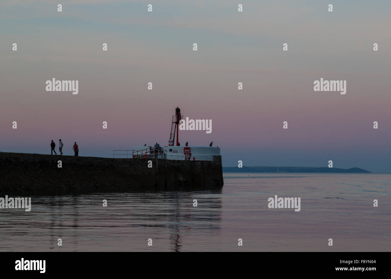 Les gens qui marchent le long de la jetée banjo dans east looe au coucher du soleil Banque D'Images