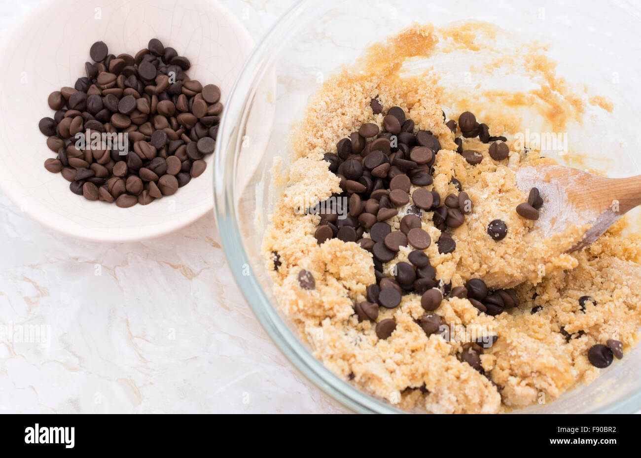 Ajouter les pépites de chocolat à la pâte à biscuits au beurre d'arachide dans un bol en verre Banque D'Images