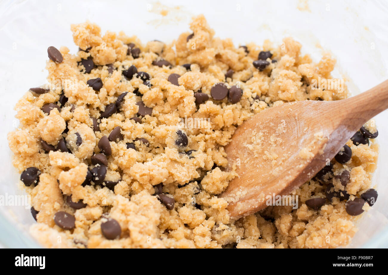 En remuant les pépites de chocolat dans la pâte à biscuits à la cuillère de bois Banque D'Images