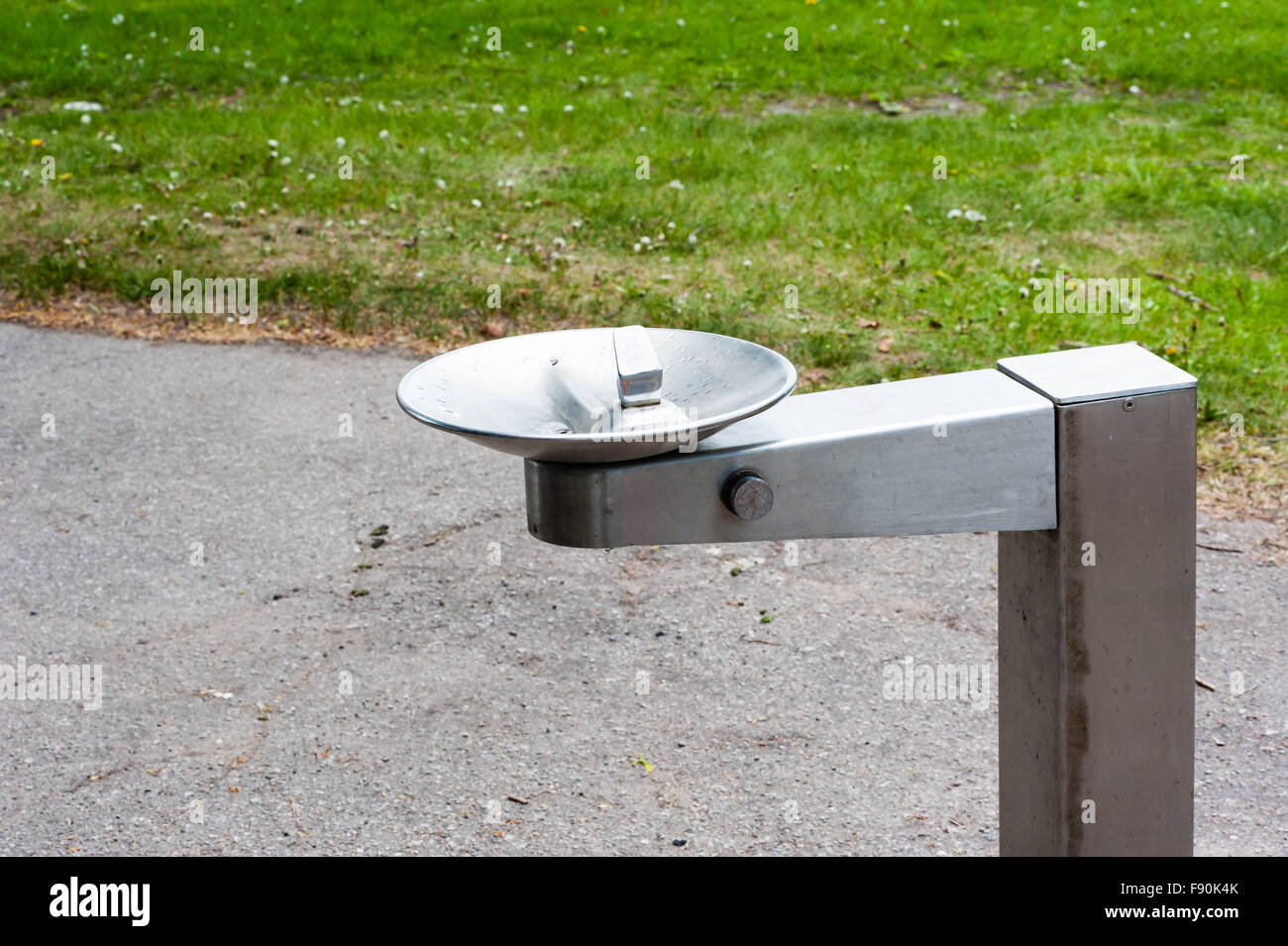 Silver metal vide eau eau potable fontaine située près de sentier du parc et de l'herbe. Banque D'Images