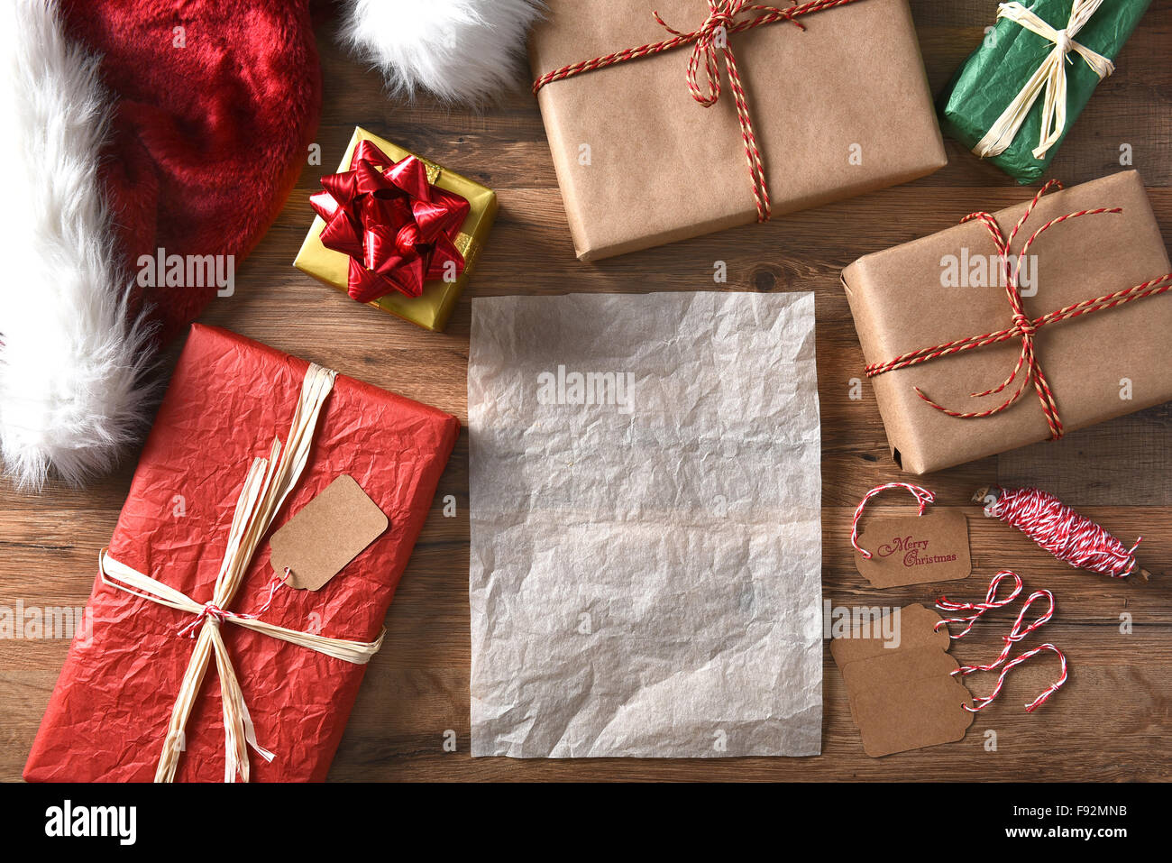 Vue supérieure de l'enveloppé de Noël sur une table en bois rustique avec de la ficelle, étiquettes cadeaux, et Santa hat. Format horizontal avec Banque D'Images