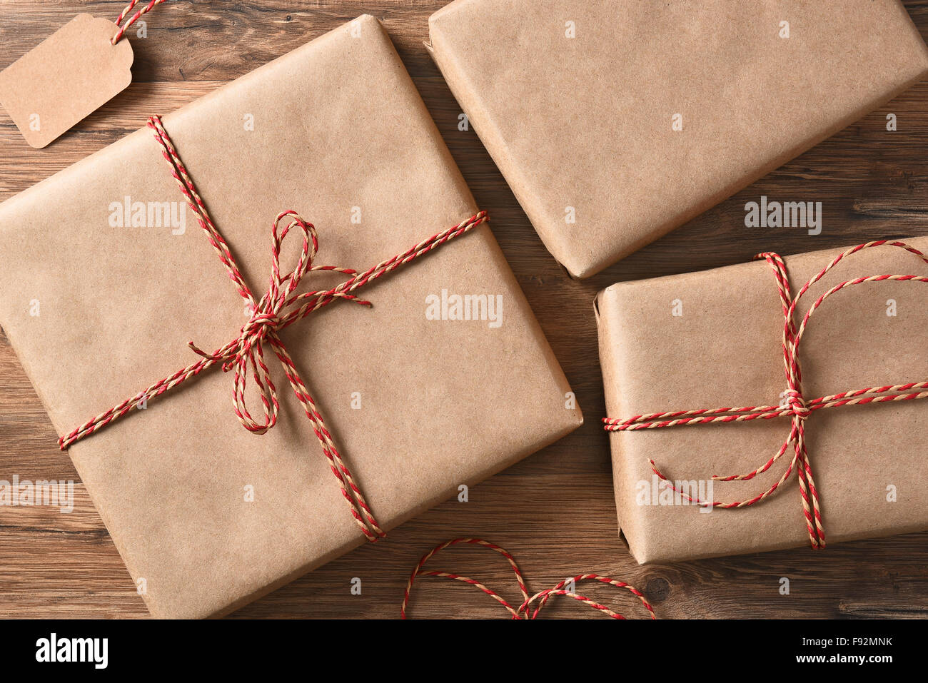 High angle view of three plain brown enveloppé dans du papier de Noël sur une table en bois rustique. Banque D'Images