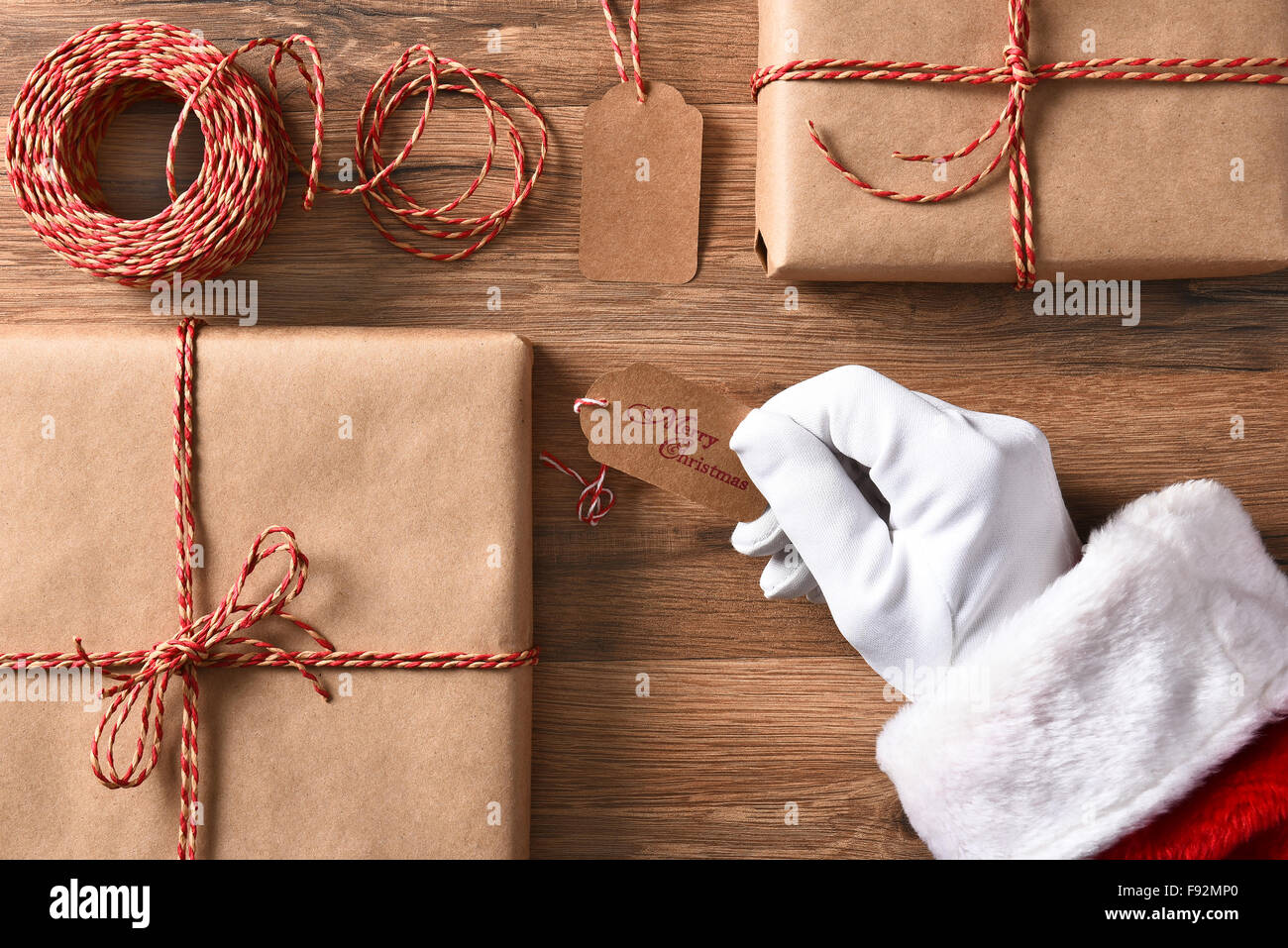 Portrait du Père Noël hand holding a gift tag avec Joyeux Noël. Libre avec gifts et chaîne. Banque D'Images