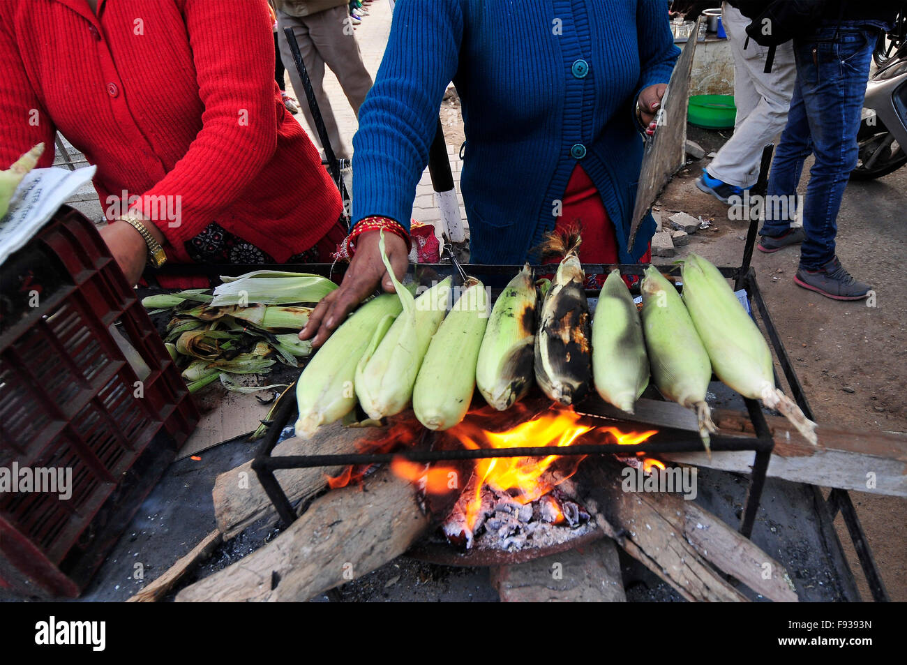 Katmandou, Népal. 13 Décembre, 2015. Kamala Subedi (pull bleu), 38 ans et d'Alisa Khadka (pull rouge), 30 ans, résident permanent du Dolkha, travaille comme vendeur de rue à Katmandou, la vente de maïs grillé. Ils ont utilisé pour acheter du maïs brut à Ric. 11 (US$ 0,11) par pièce et vendent ensuite torréfié par 25 (US$ 0,25) par pièce, où ils produisent des rapports nationaux 1500 (15$) par jour. © Narayan Maharjan/Pacific Press/Alamy Live News Banque D'Images