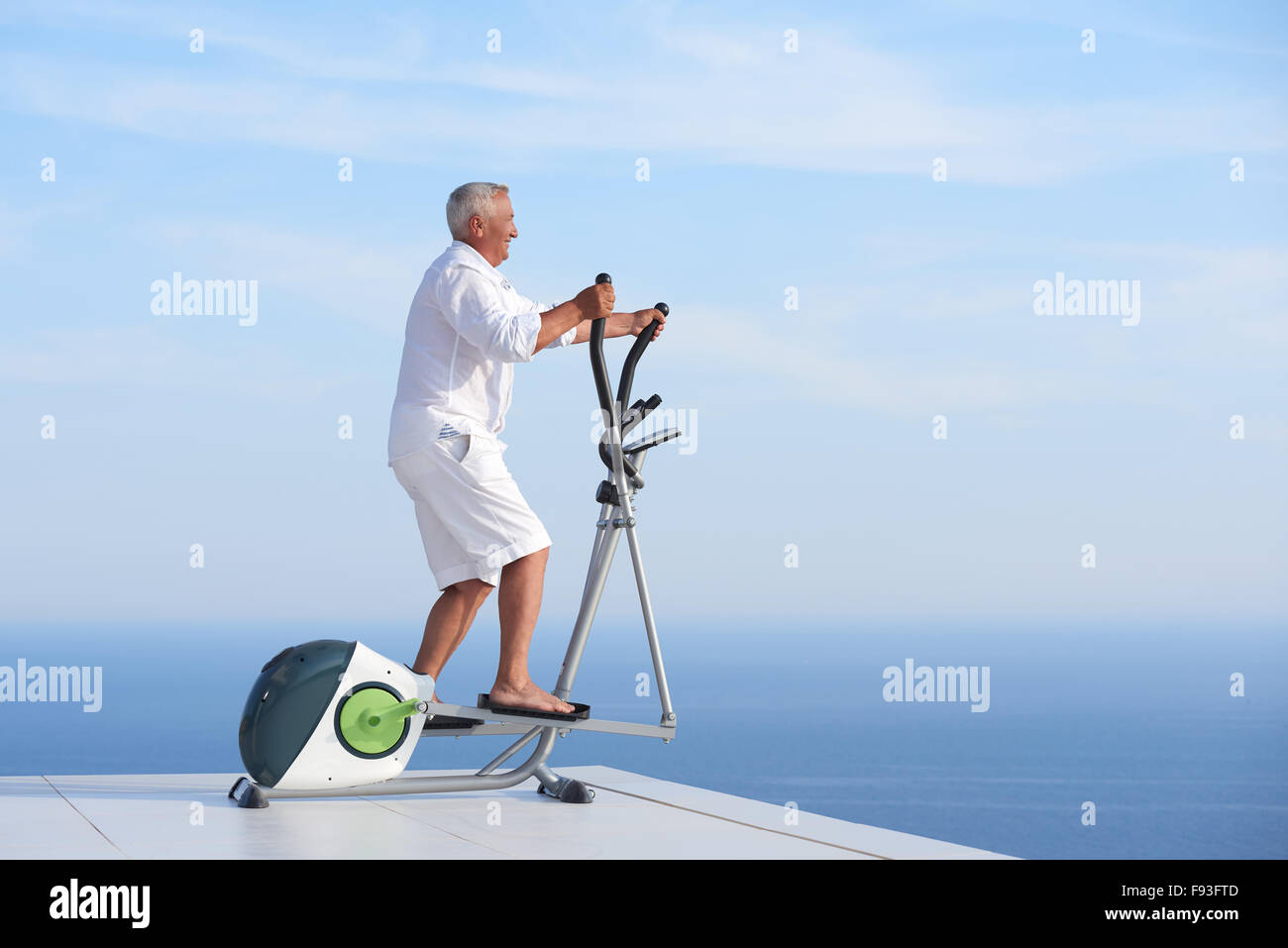 Healthy Senior homme travaillant sur le tapis de la machine à la terrasse d'accueil moderne avec vue sur l'océan Banque D'Images