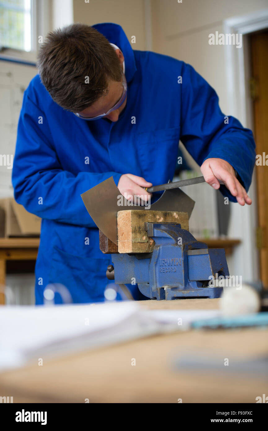 L'enseignement secondaire au Pays de Galles UK : formation professionnelle  - un adolescent portant salopette bleue le dépôt d'une pièce de métal  découpé tenue dans un étau dans une classe atelier de