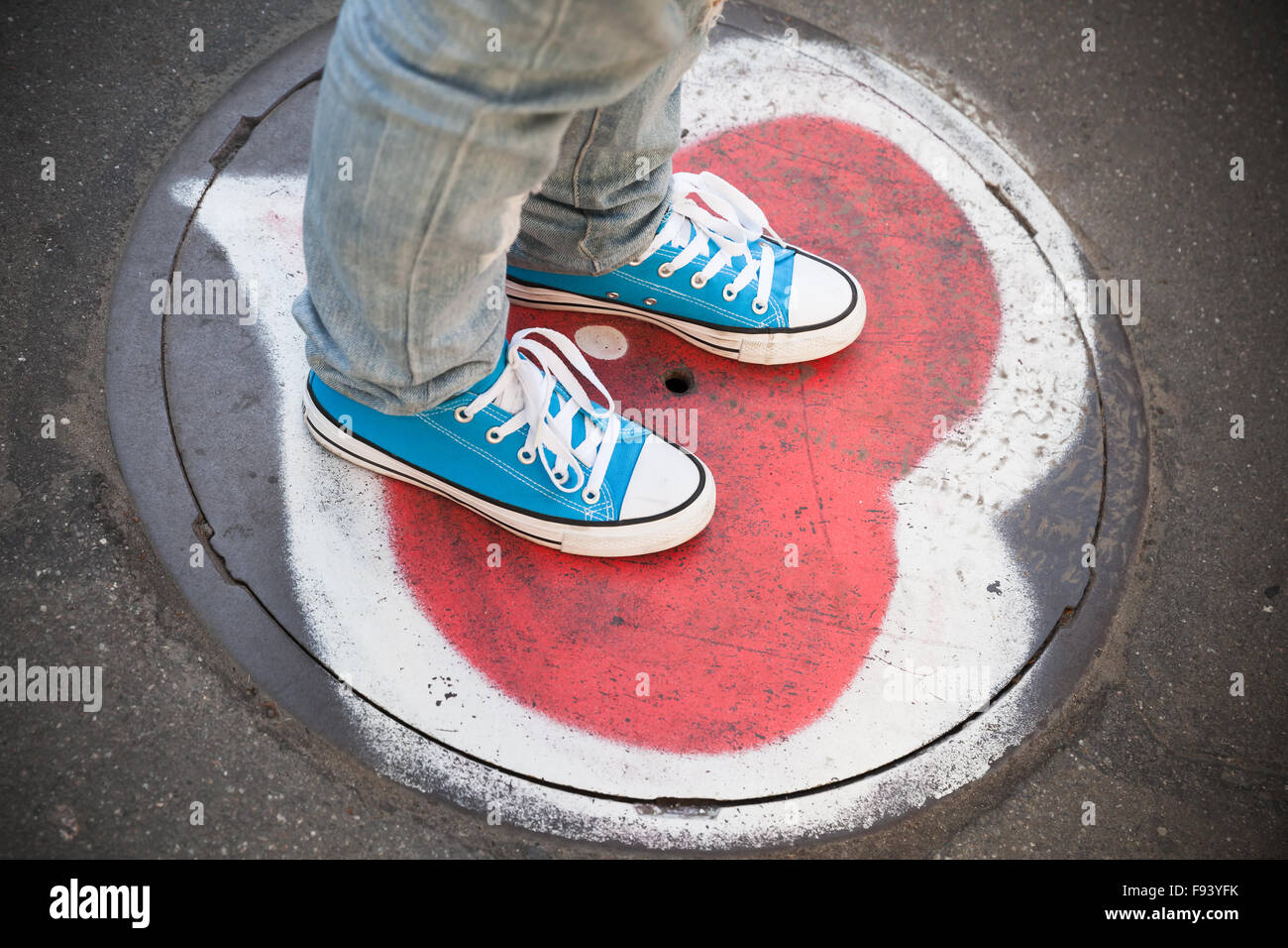 Espadrilles bleu adolescent, se tenir sur les pieds d'égout urbaines avec coeur soupir Banque D'Images