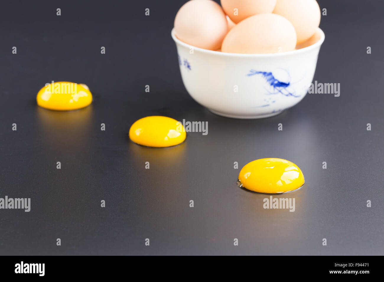 Trois d'œuf dans une rangée sur noir avec un bol d'œufs Banque D'Images