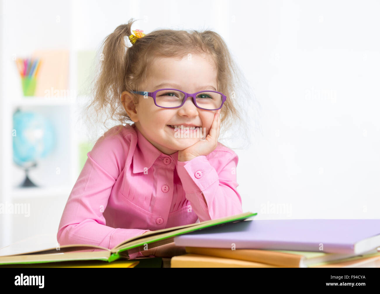 Smiling girl wearing spectacles reading book Banque D'Images