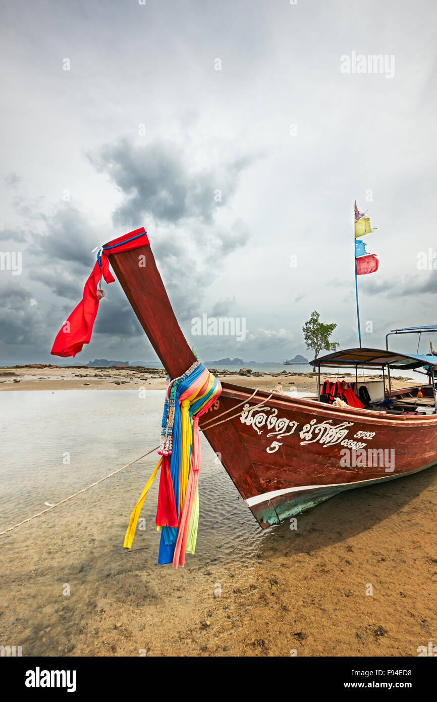 Bateau longtail thailandais traditionnel décoré avec des rubans colorés sur la proue amarré à Klong Muang Beach. La province de Krabi, Thaïlande. Banque D'Images