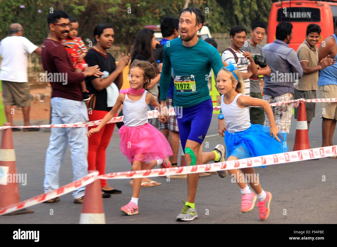 Goa, Inde. 13 Décembre, 2015. Un coureur de marathon est rejoint par sa fille sur la ligne d'arrivée, de la Goa River Marathon annuel le 13 décembre 2015, à Vasco. Goa-India Credit : Joviton Dcosta/Alamy Live News Banque D'Images