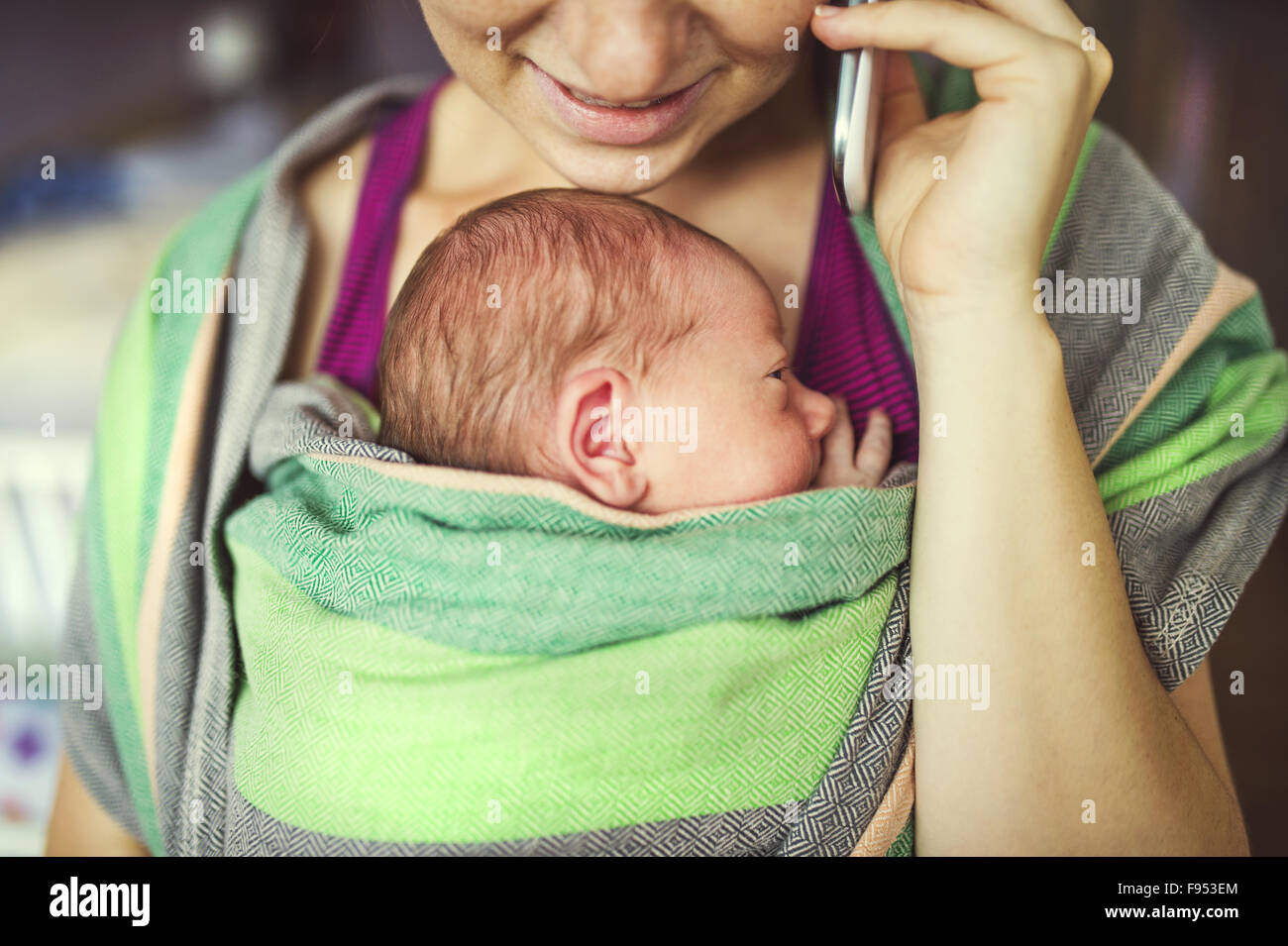 Bébé nouveau-né attente par mère-bébé dans le transporteur. Maman avec escale au téléphone. Banque D'Images