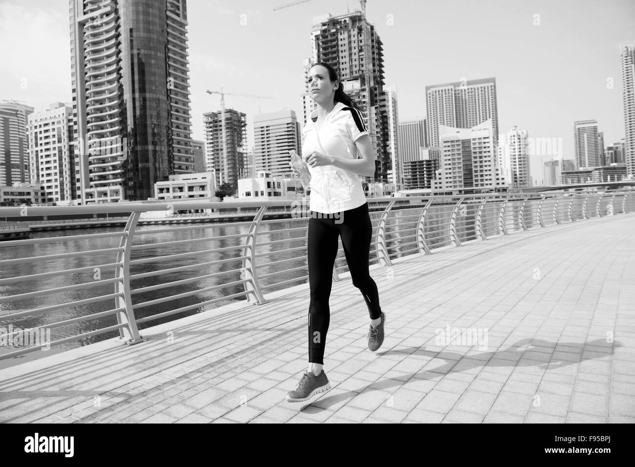 S'exécutant dans city park. Woman runner jogging à l'extérieur matin avec Dubaï scène urbaine en arrière-plan Banque D'Images