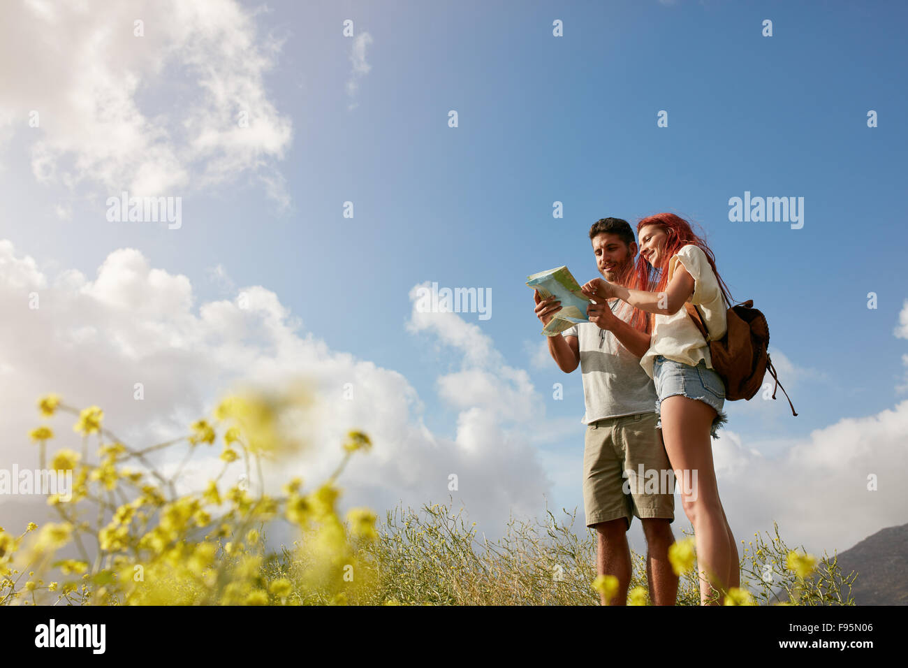 Jeune couple reading map on country walk. Caucasian hiker couple sur la randonnée à la carte directions un jour d'été. Banque D'Images