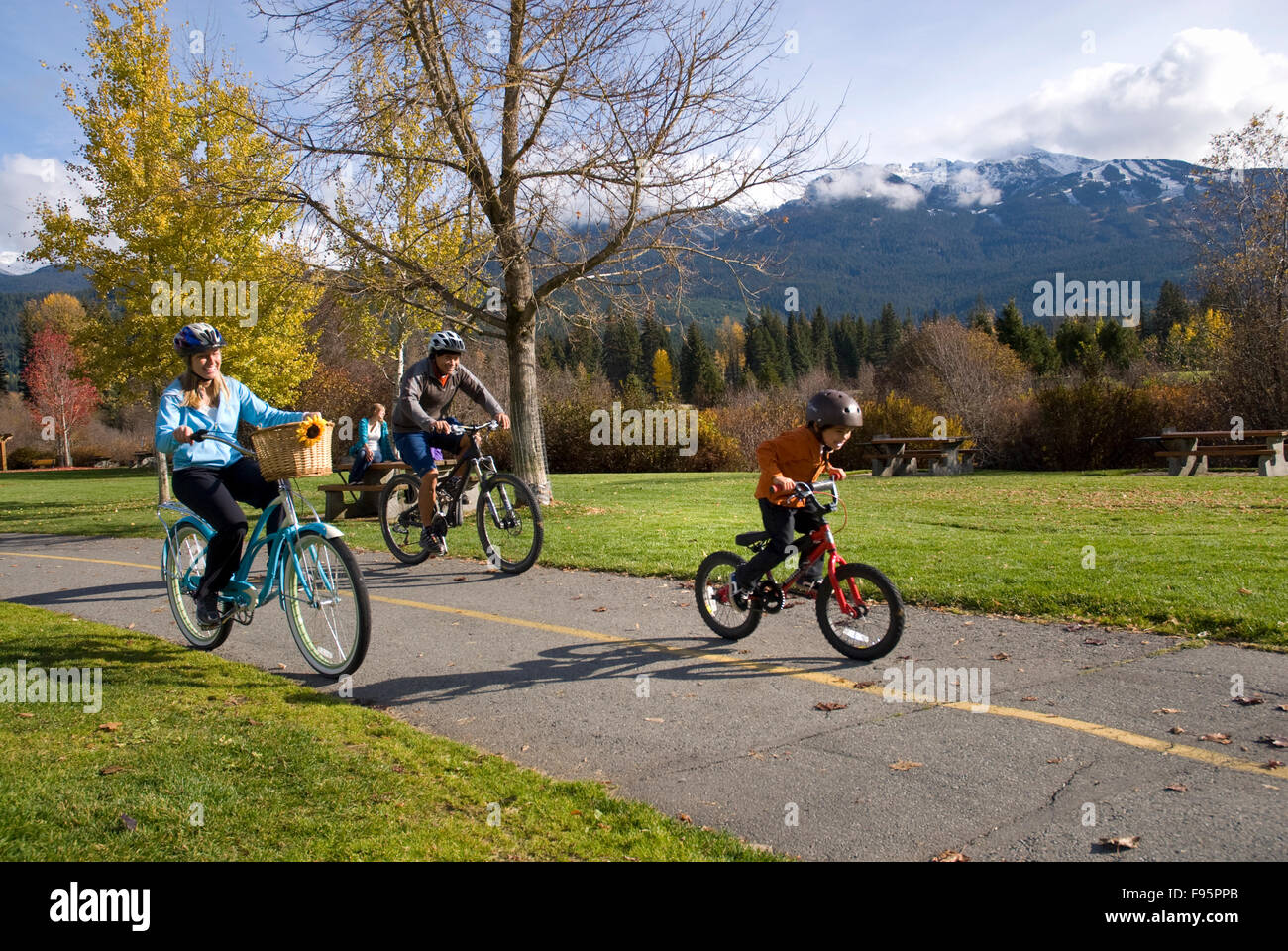 Une famille de vélos le long du sentier près de Meadow Park Recreation Centre, le long de la rivière des rêves d'or. Whistler Mountain s'élève à Banque D'Images