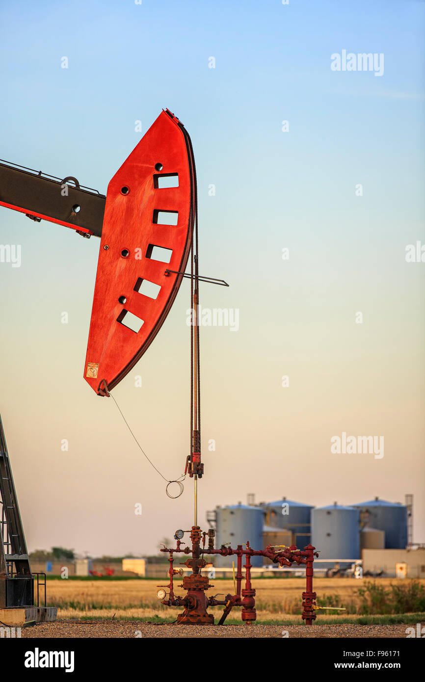 Jack la pompe à huile dans le champ de pétrole de Bakken, avec des réservoirs de stockage de pétrole en arrière-plan, près d'Estevan, Saskatchewan, Canada Banque D'Images