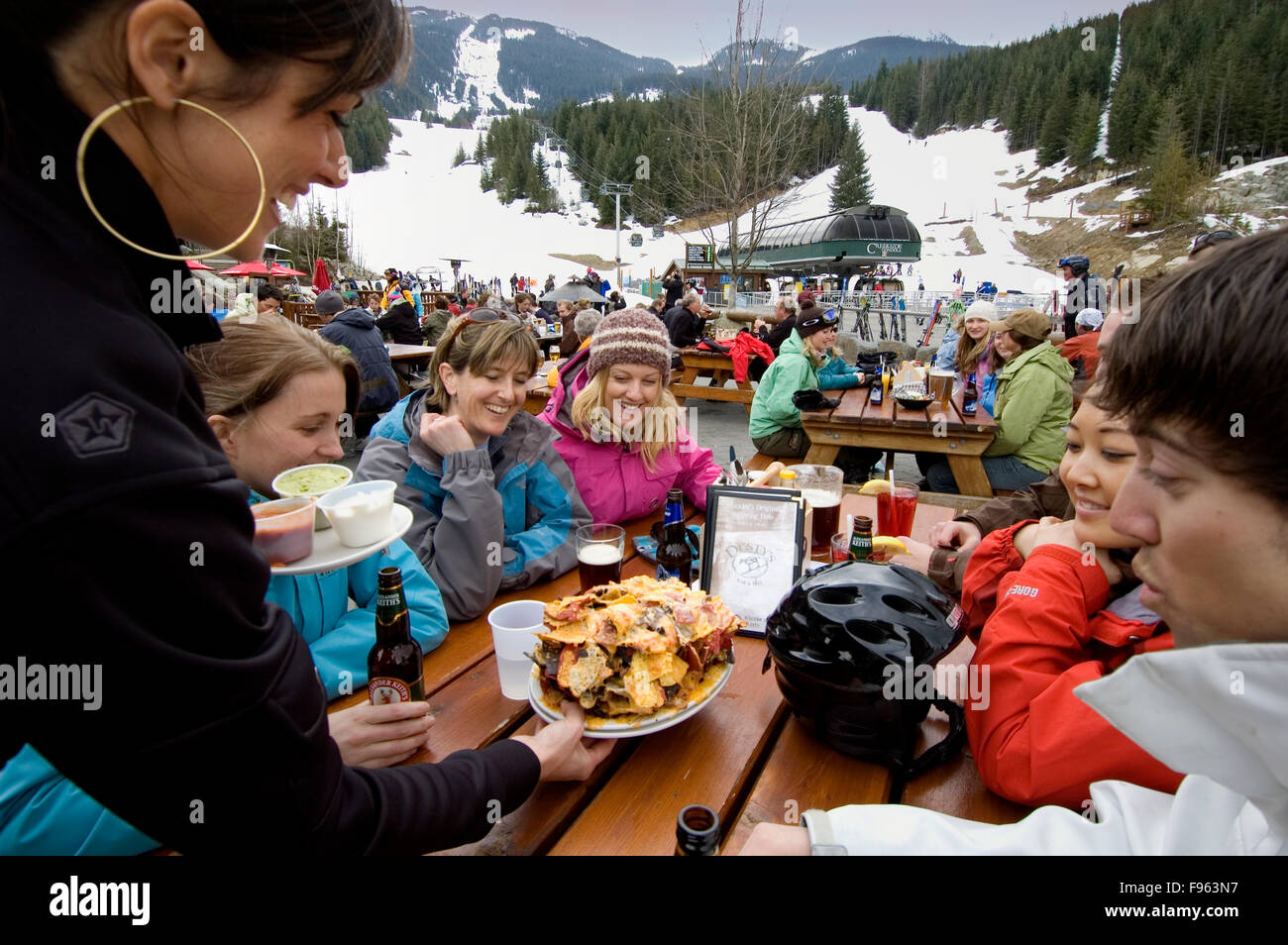 Suzy le serveur offre une énorme assiette de nachos à un groupe de skieurs de détente à Dusty's Restaurant, après une journée de ski à Whistler Banque D'Images