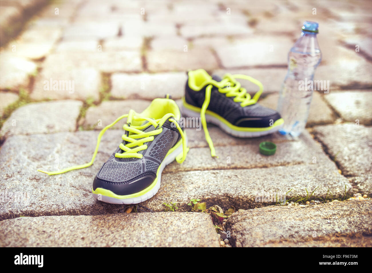 Des chaussures de course et une bouteille d'eau à gauche sur la chaussée carrelée dans le vieux centre-ville Banque D'Images