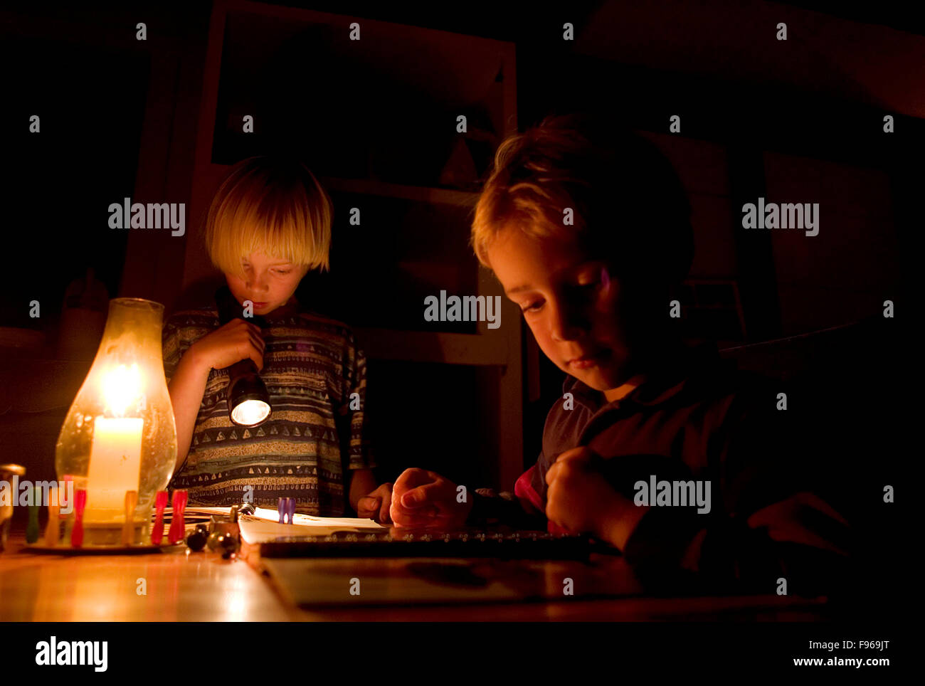 Un garçon se lit par la lumière de bougie juste avant le coucher. Banque D'Images