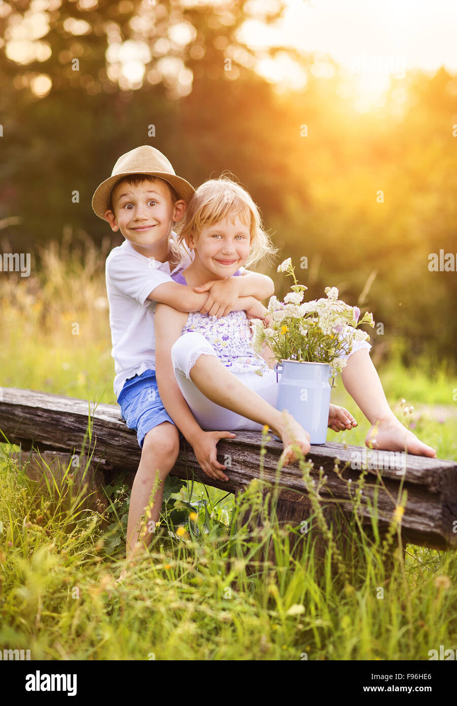 Cute boy and girl dans l'amour. Ils assis sur un banc au coucher du soleil. Banque D'Images