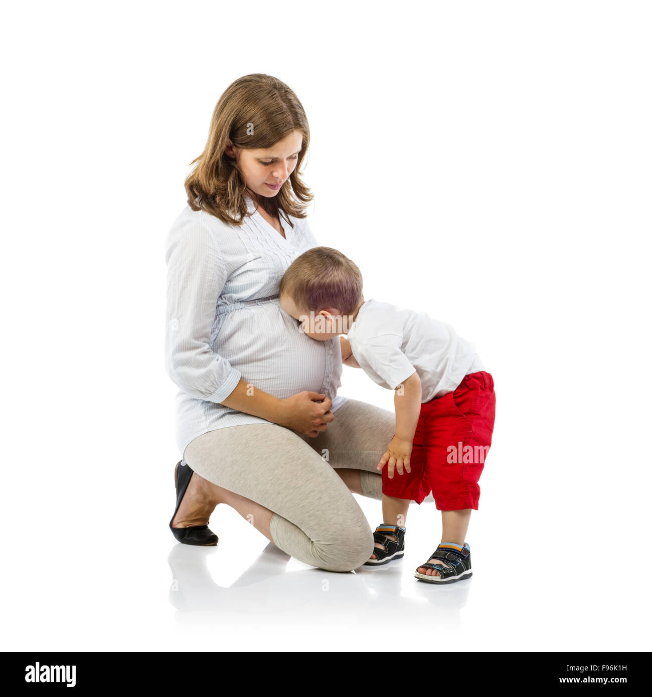 Portrait de l'heureuse mère enceinte avec son fils s'embrasser son ventre, isolé sur fond blanc Banque D'Images