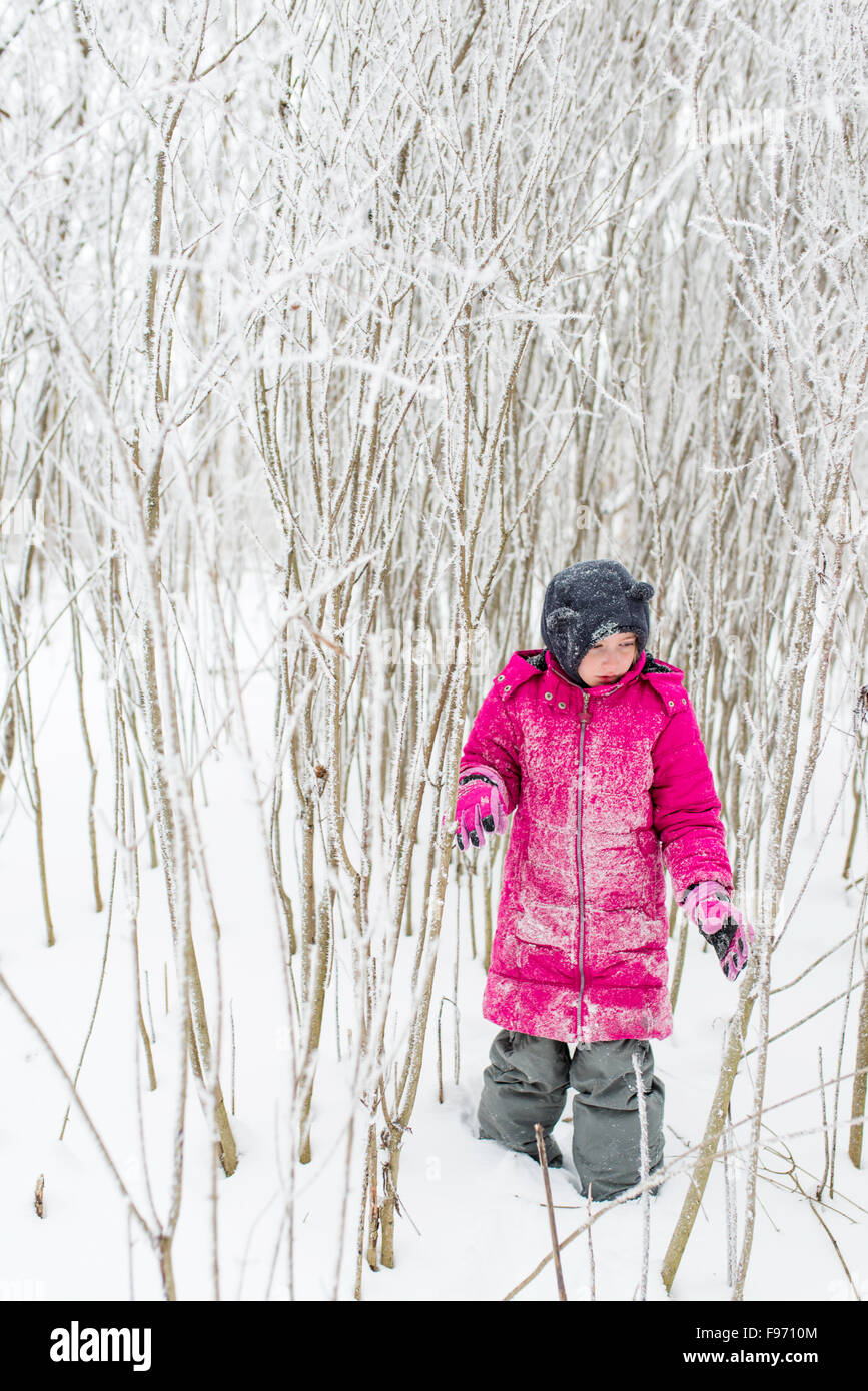 Jeune fille qui marche à travers la forêt d'hiver enneigé avec manteau rose Banque D'Images