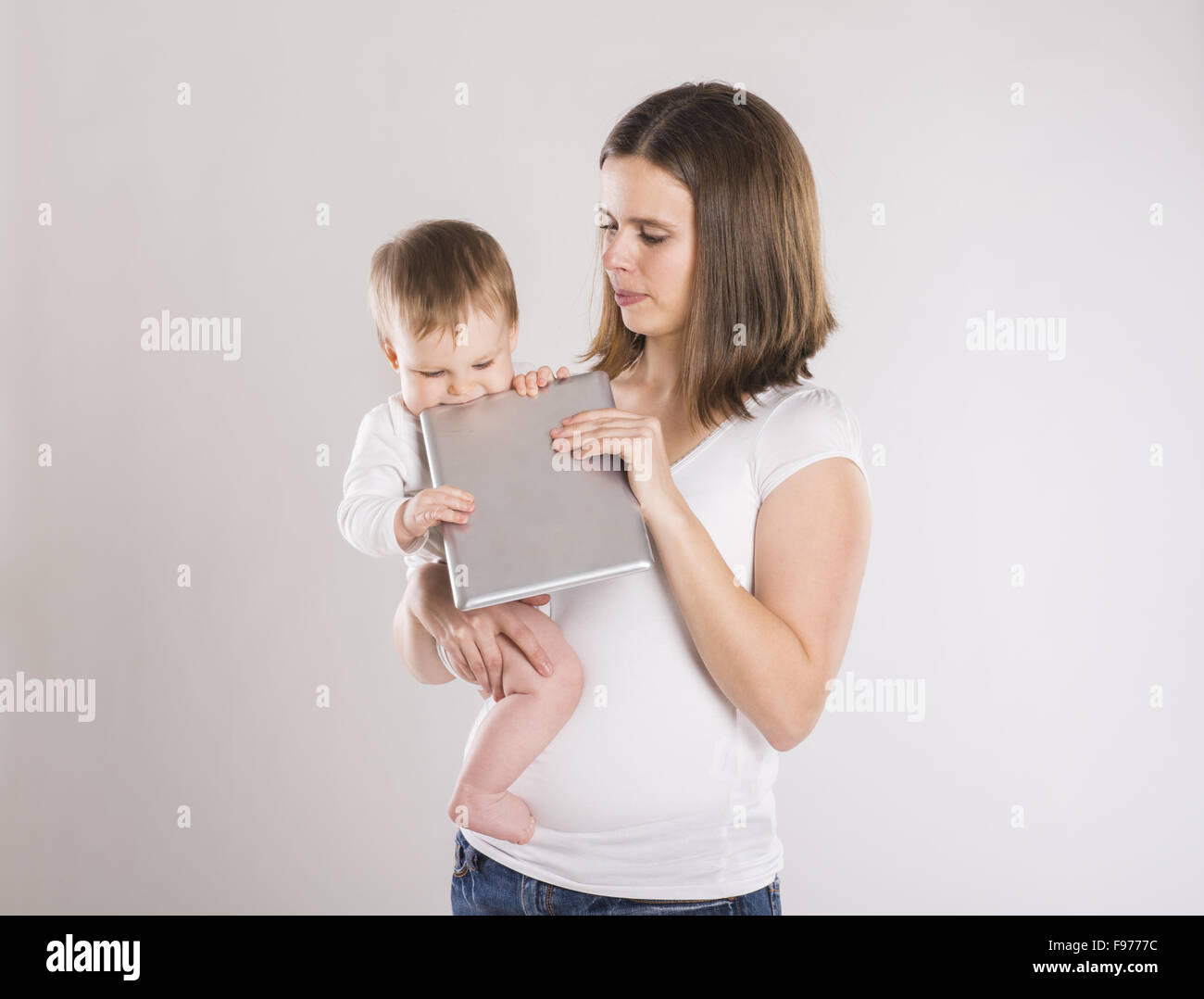 Mère et bébé avec tablette numérique. Isolé sur fond gris. Banque D'Images