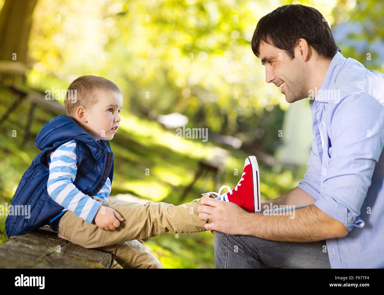 Père aide son fils à nouer ses lacets en été la nature Banque D'Images