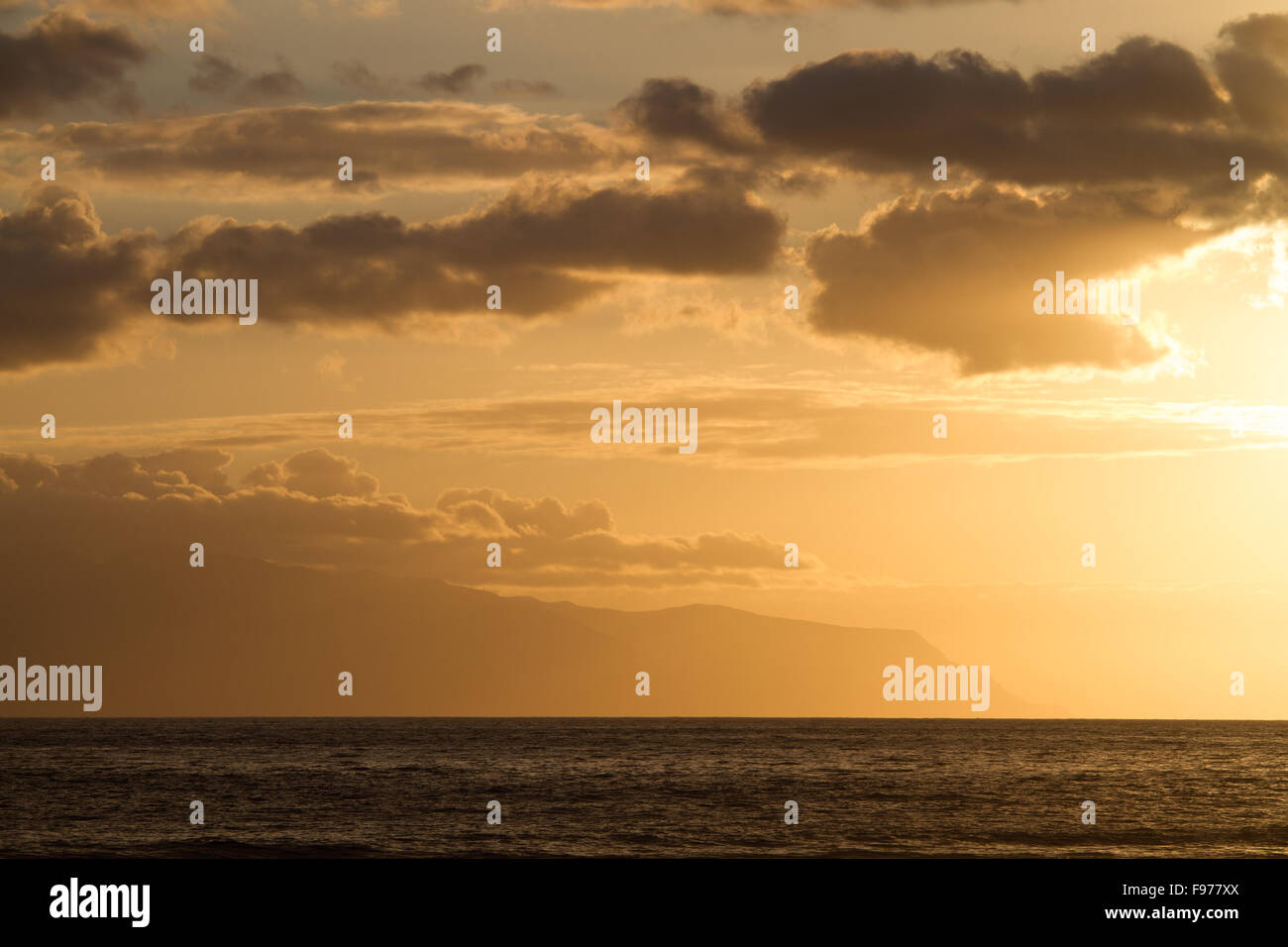 Coucher de soleil sur l'océan ciel coloré en sépia. Dans l'arrière-plan - les nuages et les montagnes de l'île voisine. Banque D'Images