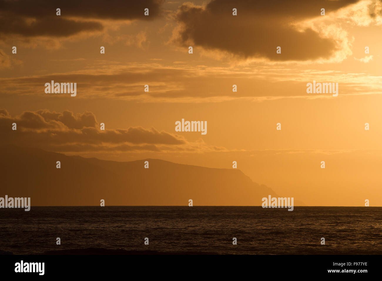 Coucher de soleil sur l'océan ciel coloré en sépia. Dans l'arrière-plan - les nuages et les montagnes de l'île voisine. Banque D'Images