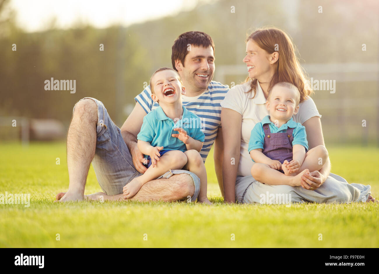 Happy Family est relaxant et assis sur un terrain de football Banque D'Images