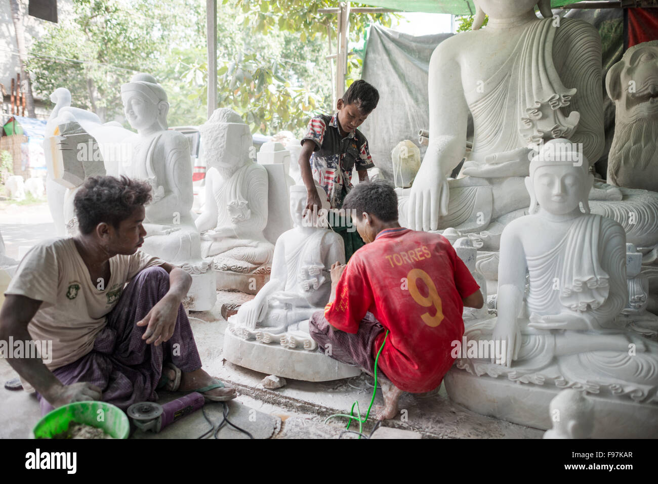 MANDALAY, Myanmar - artisans locaux engagent le travail éreintant et poussiéreux de la sculpture des statues de Bouddha en marbre. Avec le bouddhisme est la religion dominante au Myanmar, il y a une demande considérable pour les statues, avec les clients en mesure de choisir parmi une multitude de poses, de tailles et de styles. Les artisans sont regroupés dans une rue dans le quartier de Mandalay Chanmyathazi près de la Pagode Mahamuni. Banque D'Images