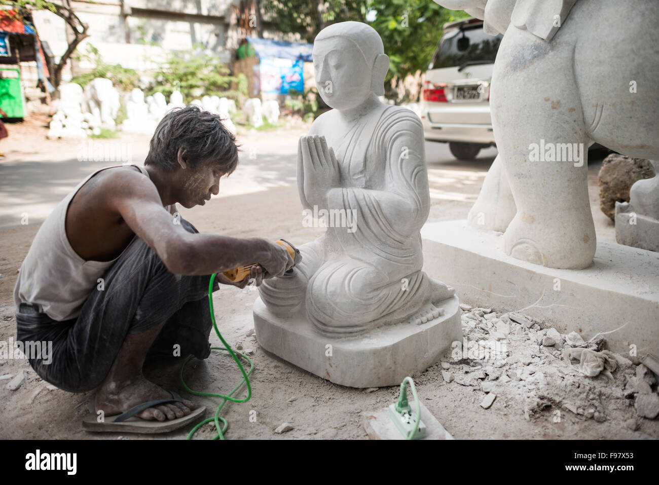 MANDALAY, Myanmar - artisans locaux engagent le travail éreintant et poussiéreux de la sculpture des statues de Bouddha en marbre. Avec le bouddhisme est la religion dominante au Myanmar, il y a une demande considérable pour les statues, avec les clients en mesure de choisir parmi une multitude de poses, de tailles et de styles. Les artisans sont regroupés dans une rue dans le quartier de Mandalay Chanmyathazi près de la Pagode Mahamuni. Banque D'Images