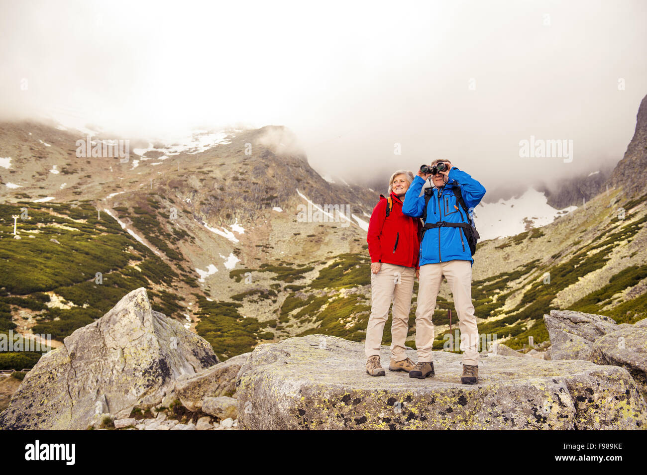 Les randonneurs Senior couple enjoying le paysage avec des jumelles Banque D'Images