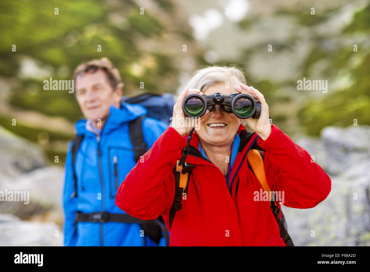 Les randonneurs Senior couple enjoying le paysage avec des jumelles Banque D'Images