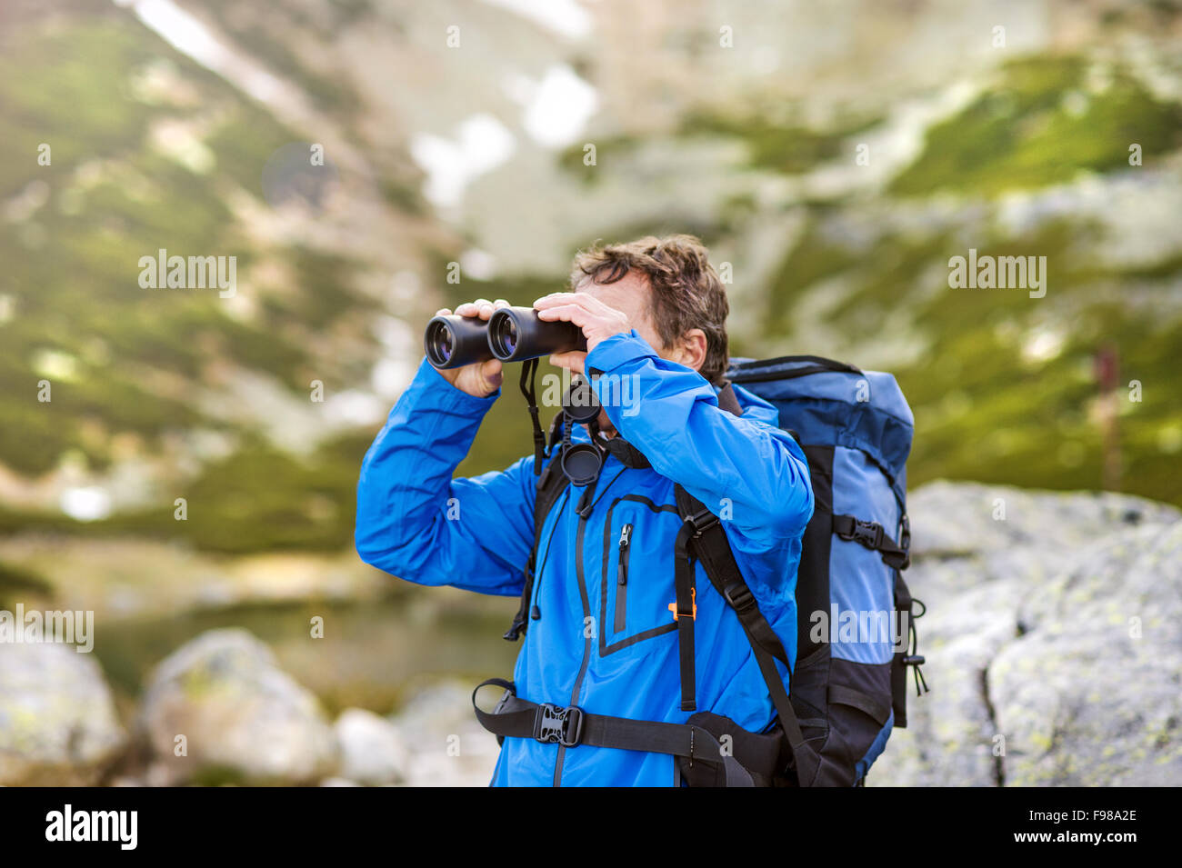 Randonneur Senior homme jouissant de la vue magnifique sur le paysage avec des jumelles pendant la randonnée. Banque D'Images