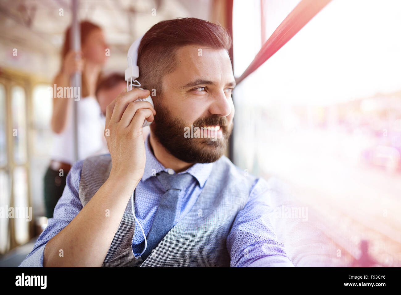 Beau hipster homme moderne avec un casque voyager en tram en ville Banque D'Images