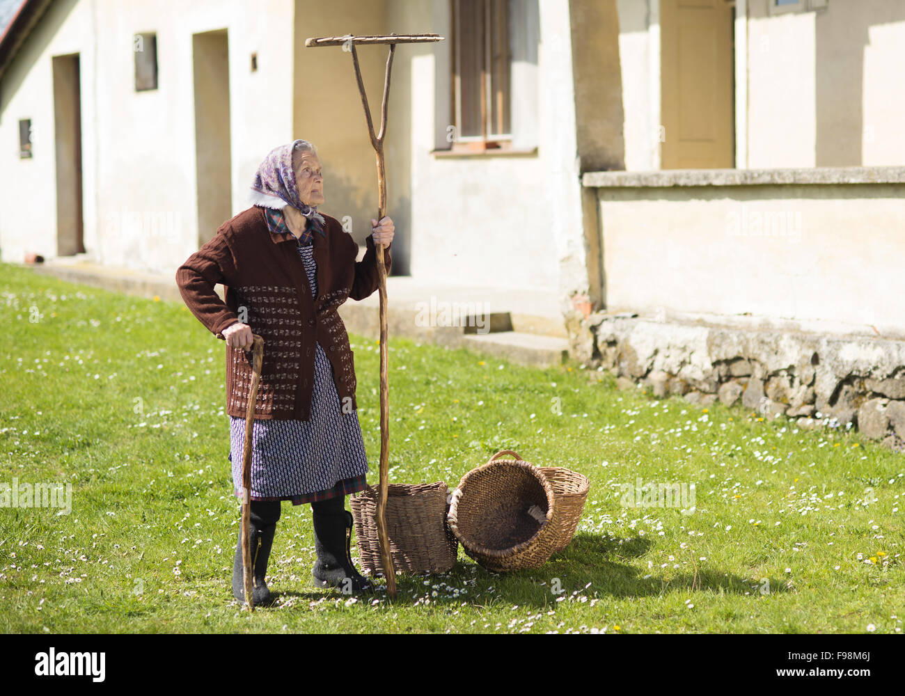 Très vieille femme en foulard avec outils de jardin dans son arrière-cour Banque D'Images