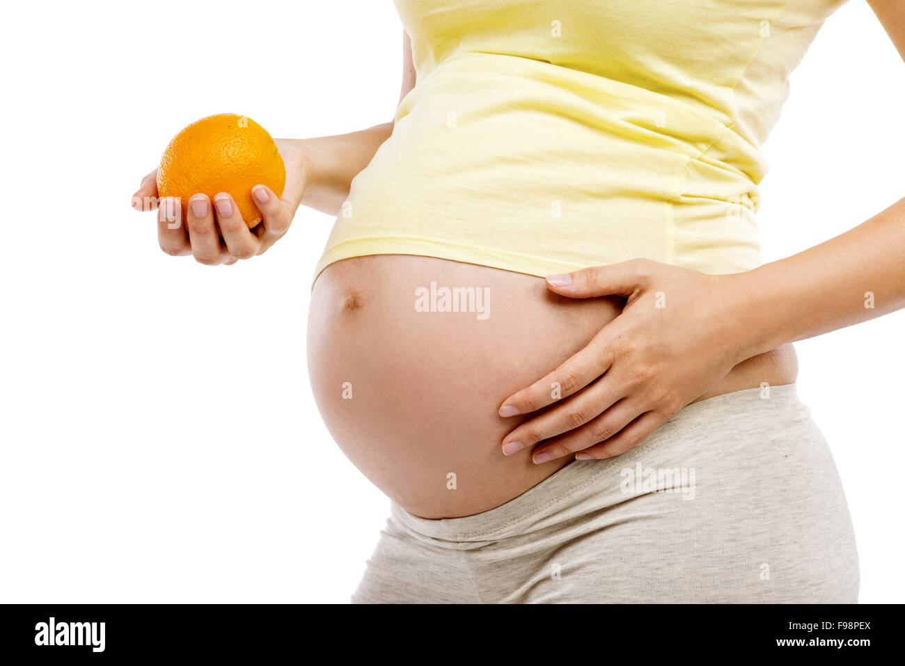 Méconnaissable pregnant woman holding orange, isolé sur fond blanc Banque D'Images
