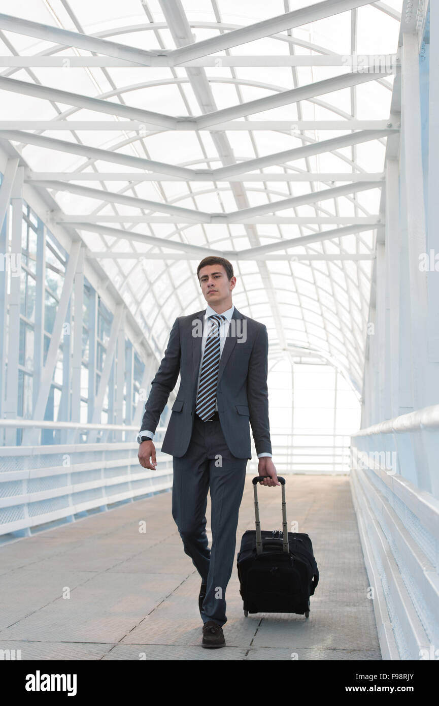 Businessman walking dans l'environnement urbain de l'aéroport avec suitcase Banque D'Images