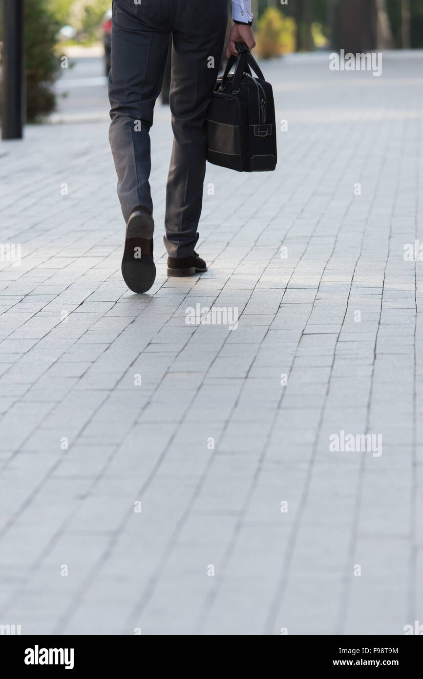 Méconnaissable businessman walking sur la rue près de l'immeuble de bureaux Banque D'Images