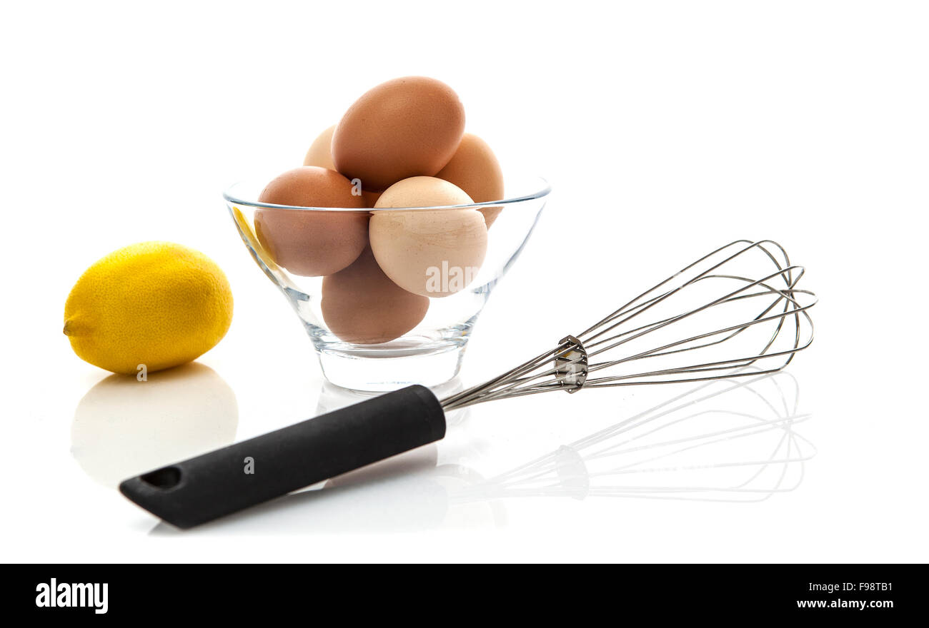 Fouet en métal avec des oeufs frais et de citron sur un fond blanc Banque D'Images