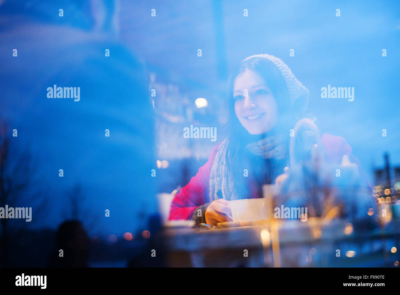 Jeune couple dans des vêtements d'hiver à parler dans le café. Réflexions à partir de windows. Banque D'Images