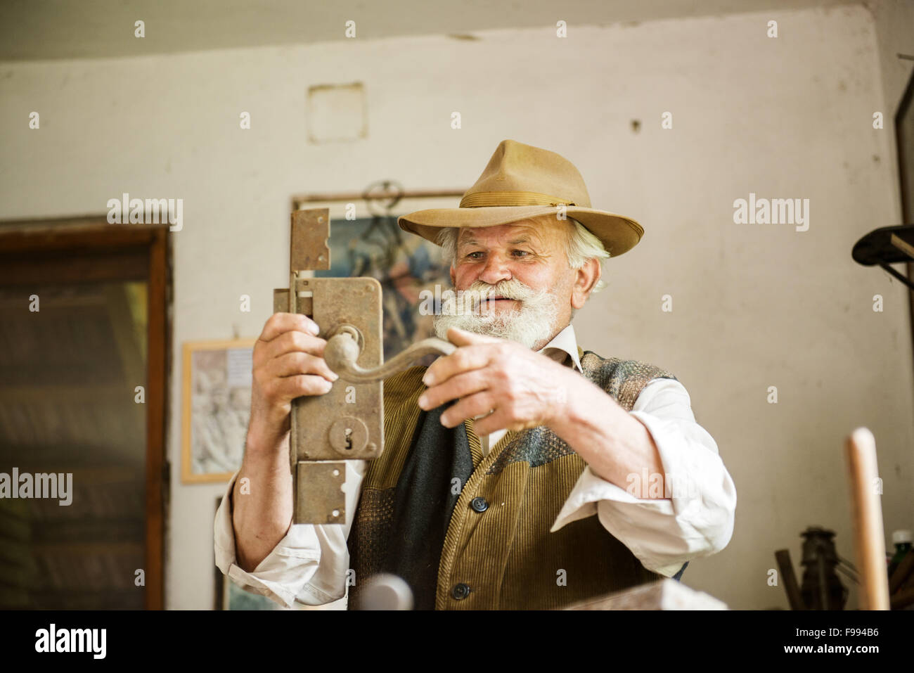 Vieux fermier avec barbe et chapeau dans son atelier Banque D'Images